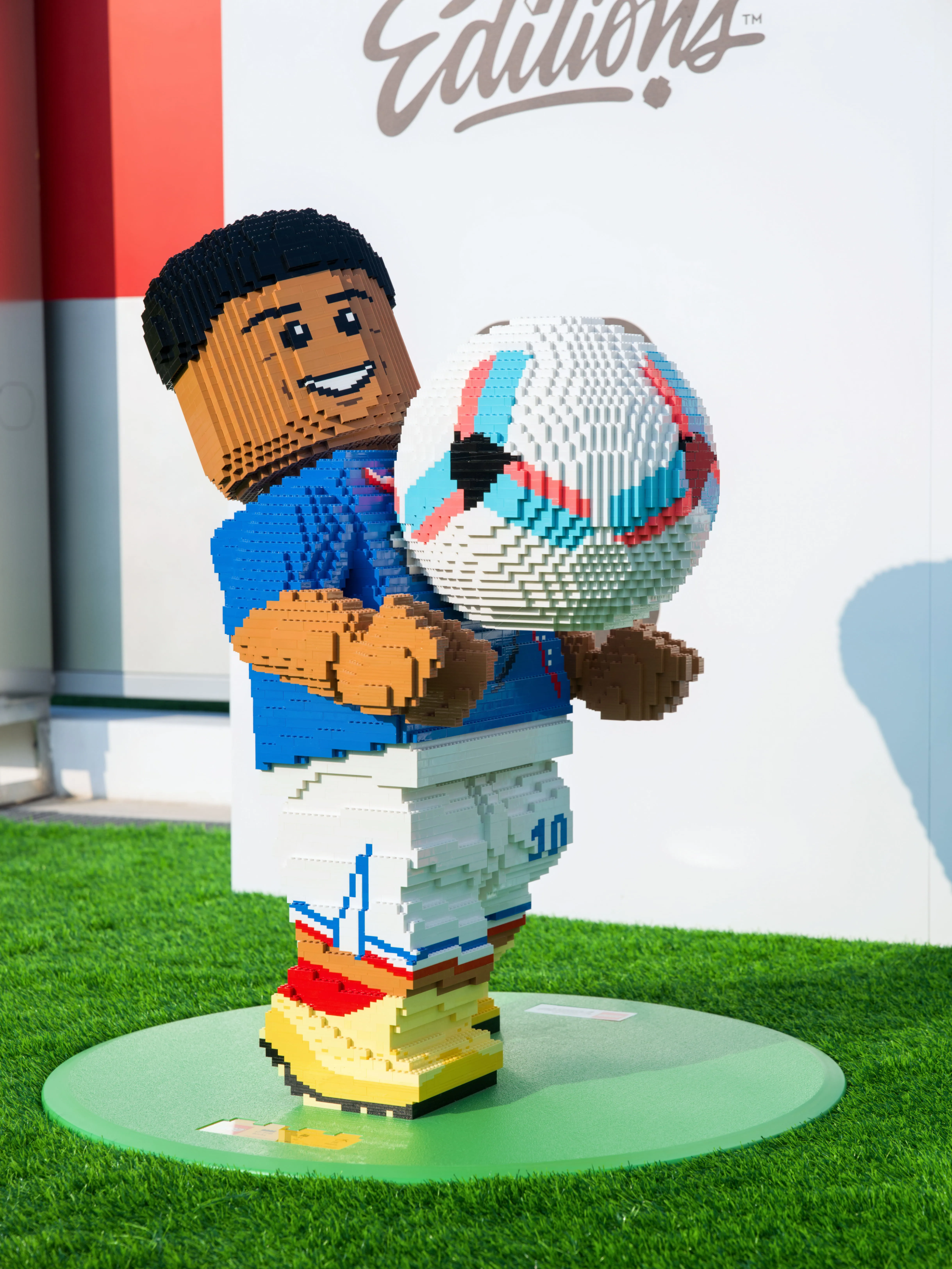 LEGO Figur eines Fußballspielers mit blauem Trikot, weißer Hose und gelben Schuhen, der einen Fußball hält